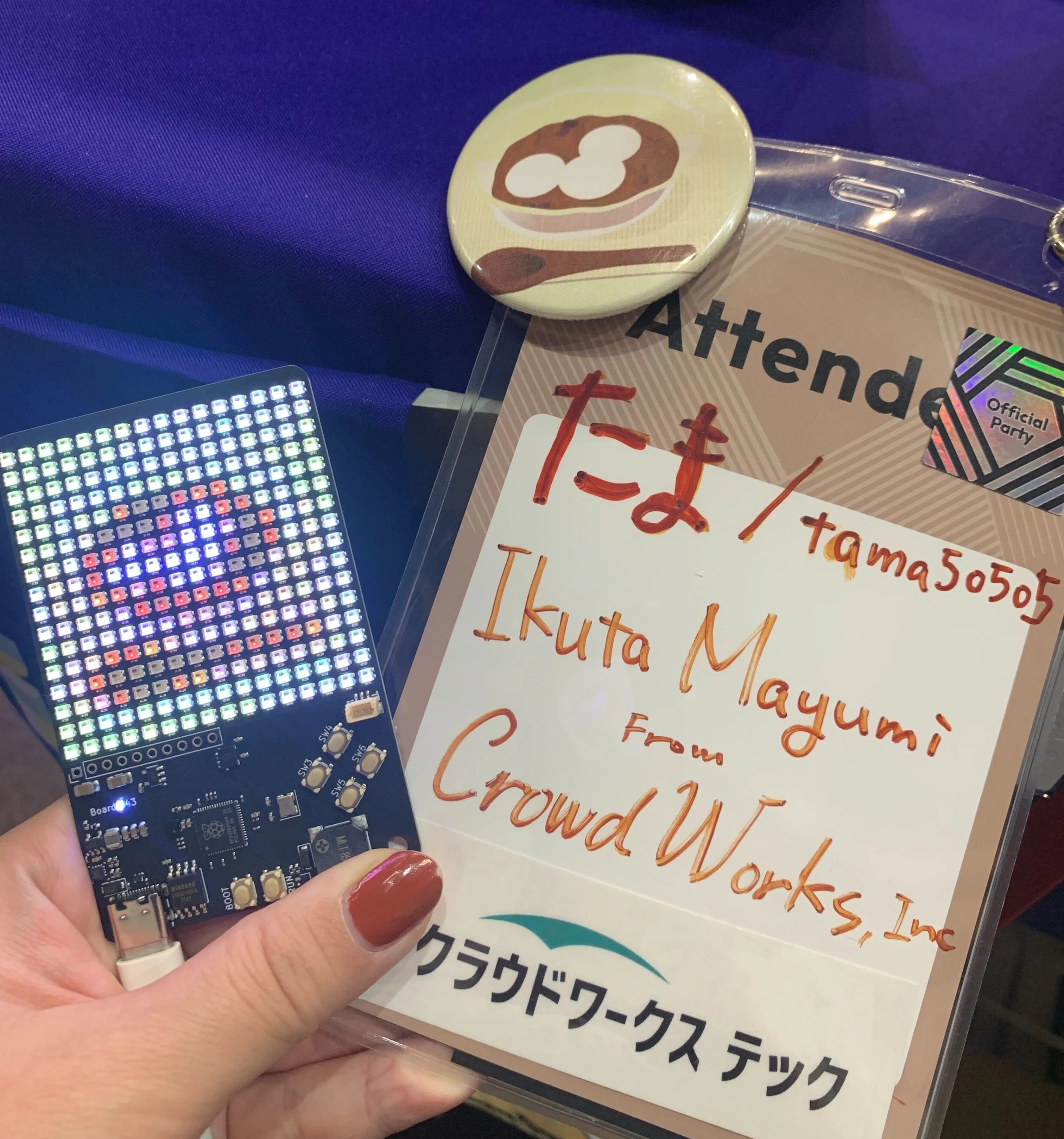 たま(tama5050)、Ikuta Mayumi、CrowdWorks Inc.と書かれたイベント参加者の名札と、カラーLEDが点灯したBoard43.jpg