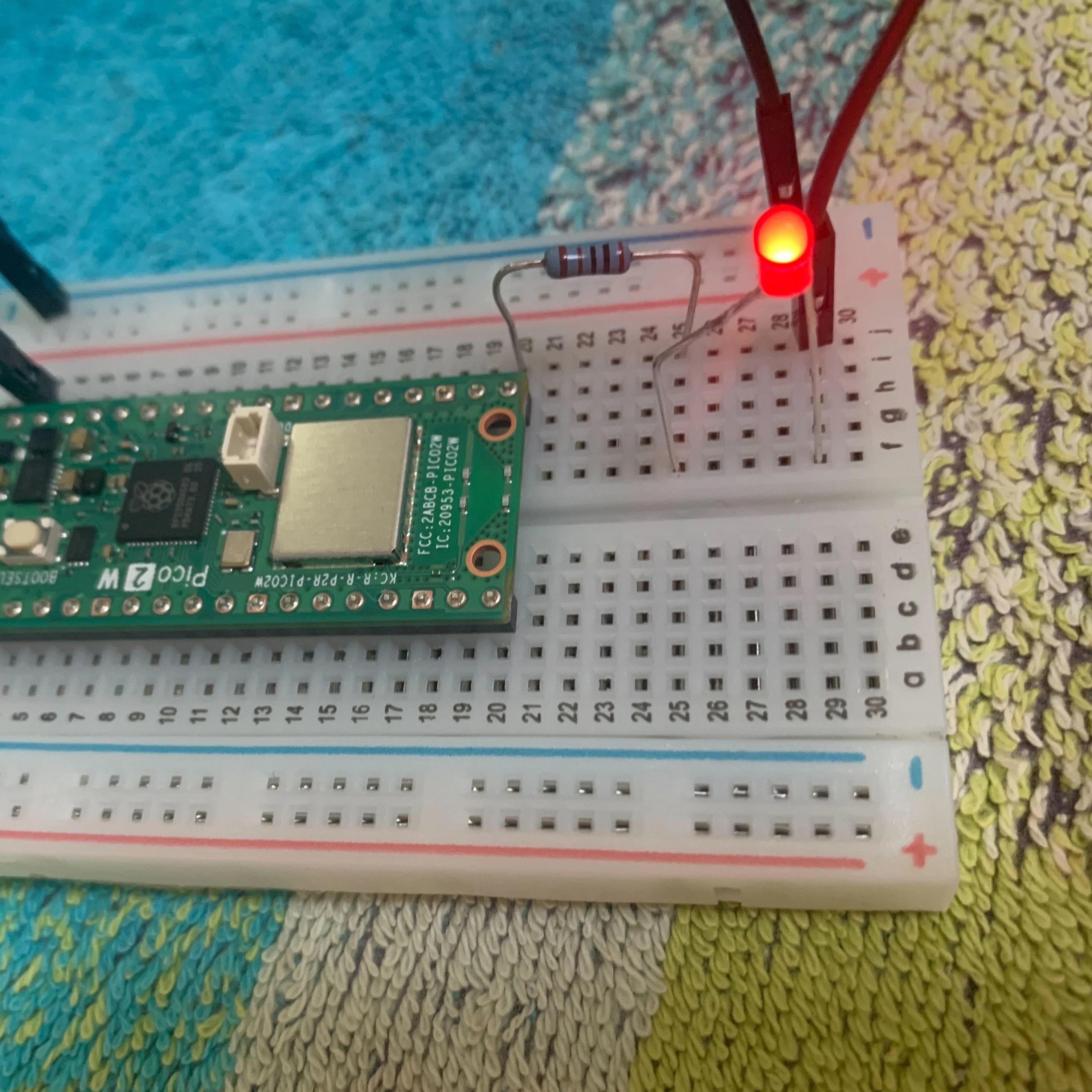 Raspberry Pi Pico 2 Wをブレッドボードに接続し、抵抗を介して赤色LEDを点灯させた電子工作の様子.jpg