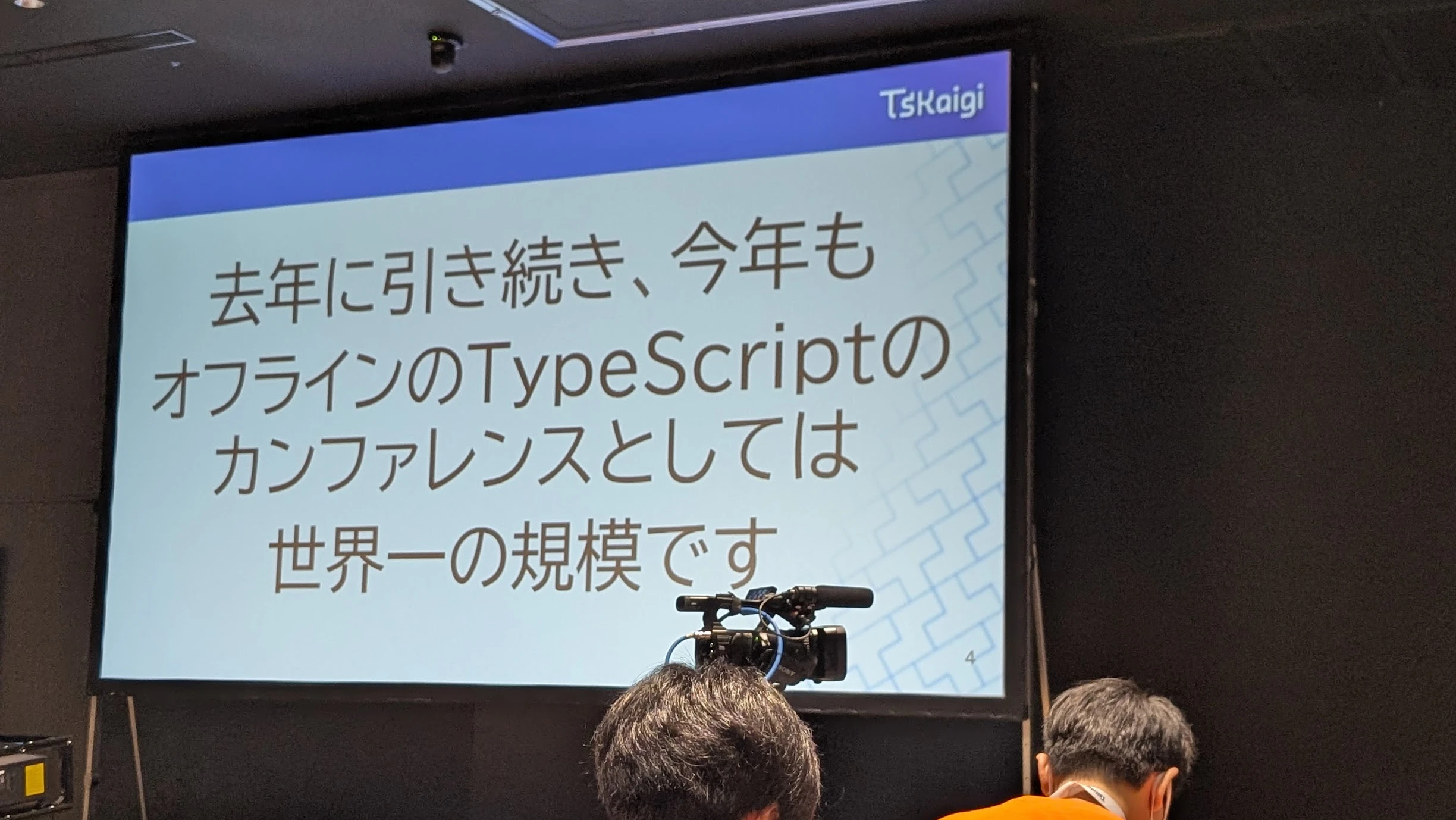TSKaigi 2026のオープニングトークで投影されたスライド。スクリーンには『去年に引き続き、今年もオフラインの TypeScript のカンファレンスとしては世界一の規模です』と表示されている。